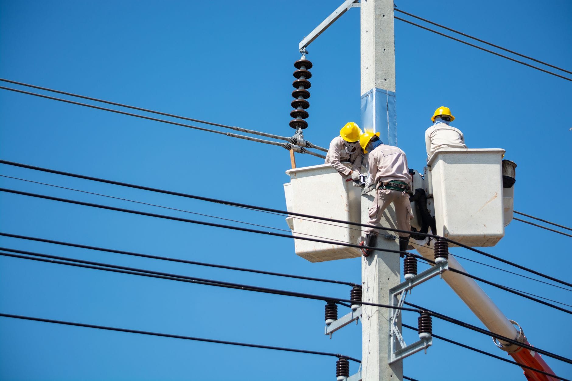 Elektrycy w kaskach pracują na liniach energetycznych w Tajlandii